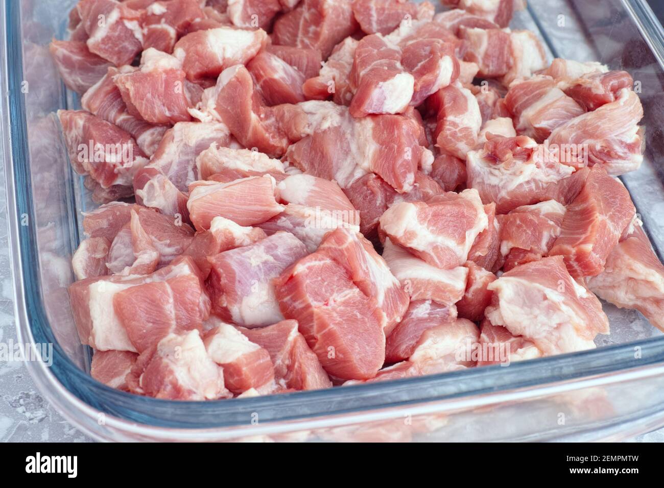 Fette di carne di maiale cruda in un vassoio di vetro primo piano. Foto Stock