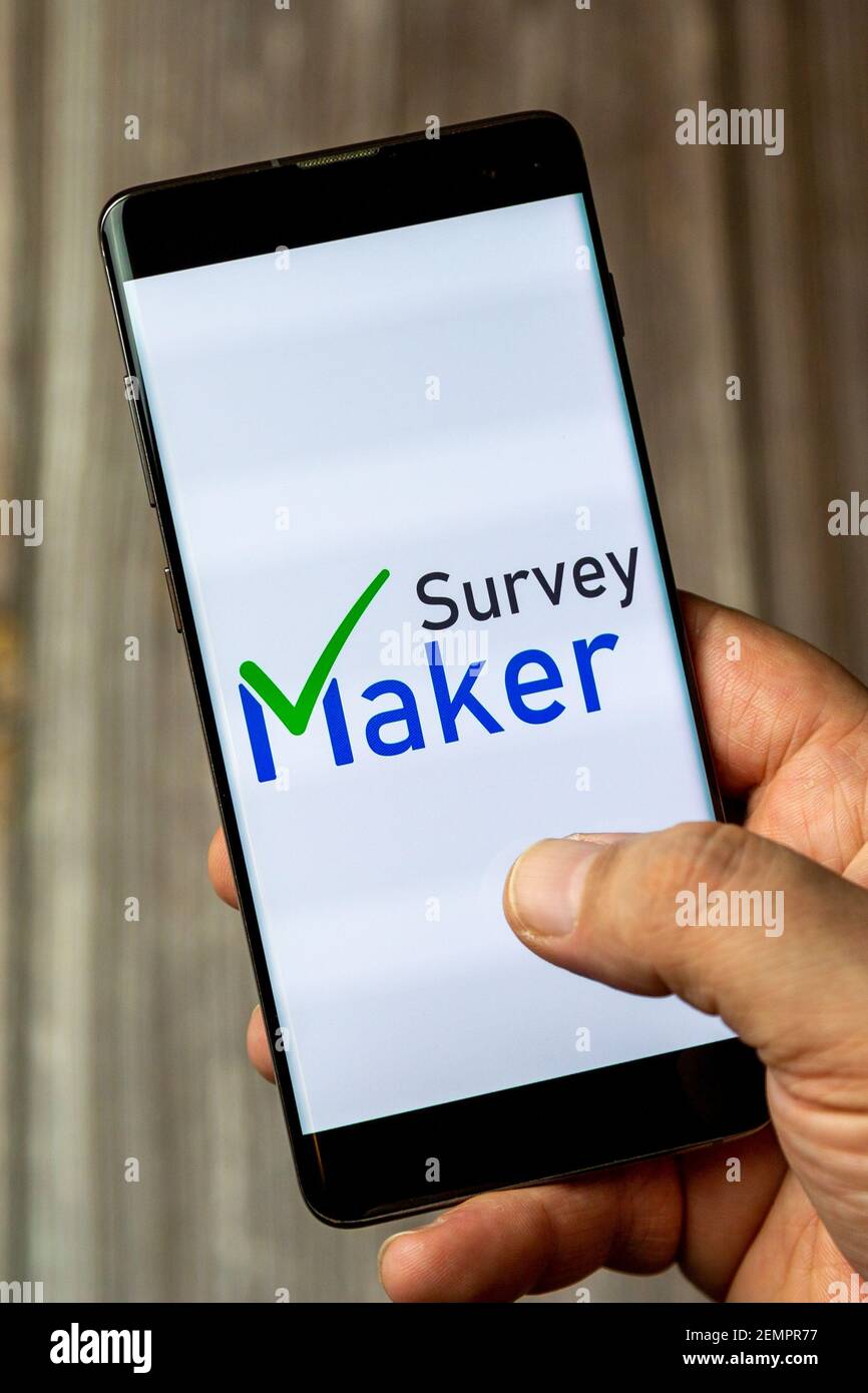 Un telefono cellulare o un telefono cellulare tenuto da un Mano con l'app Survey maker aperta sullo schermo Foto Stock
