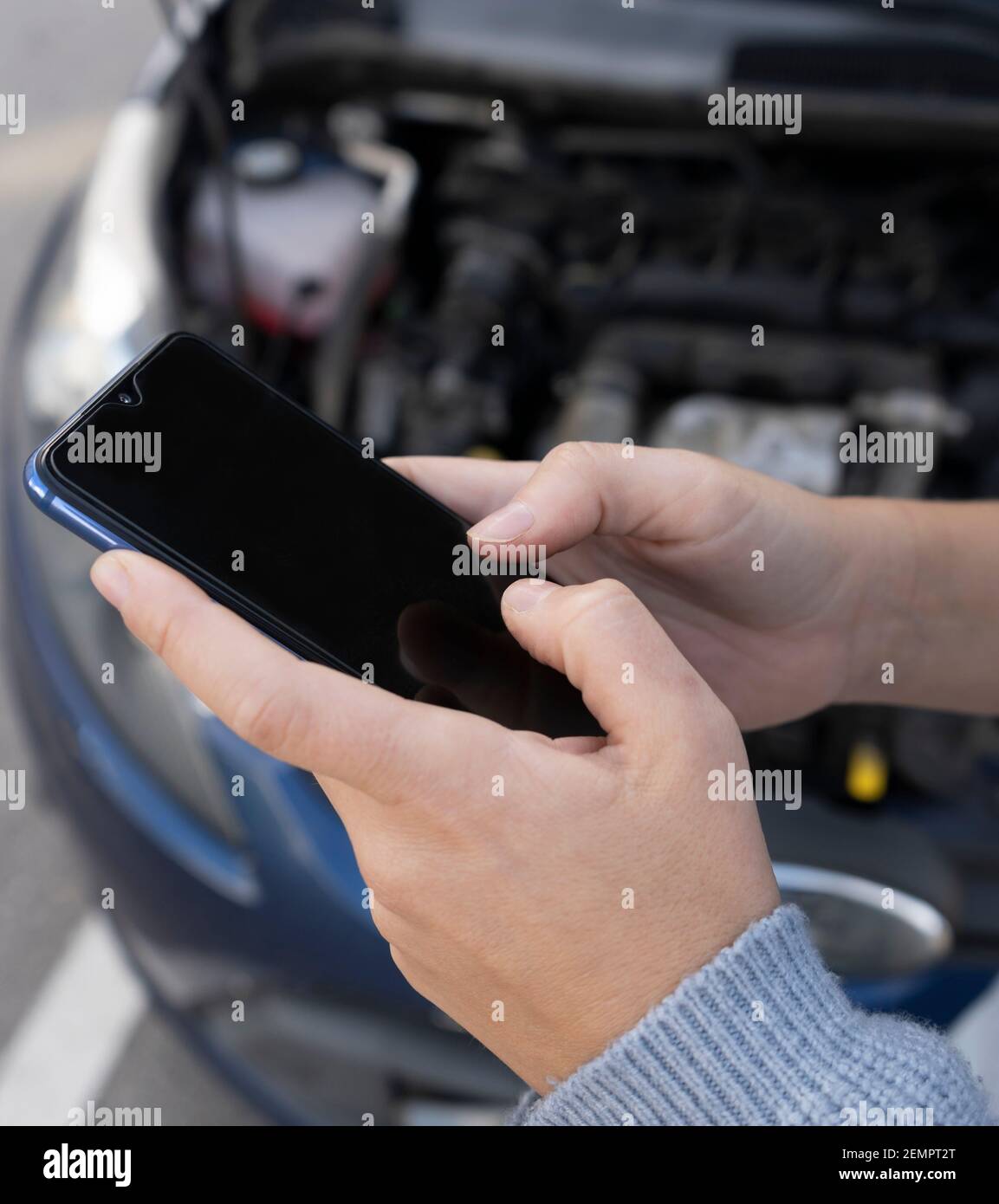 Vista closeup delle mani della donna utilizzando il telefono, SMS o utilizzare l'assicurazione app auto dopo il guasto del veicolo per l'assistenza stradale. Riparazione e incidente tr Foto Stock