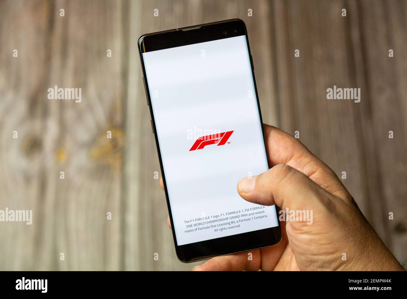 Un telefono cellulare o un telefono cellulare tenuto da un Mano con l'app F1 o Formula uno aperta schermo Foto Stock