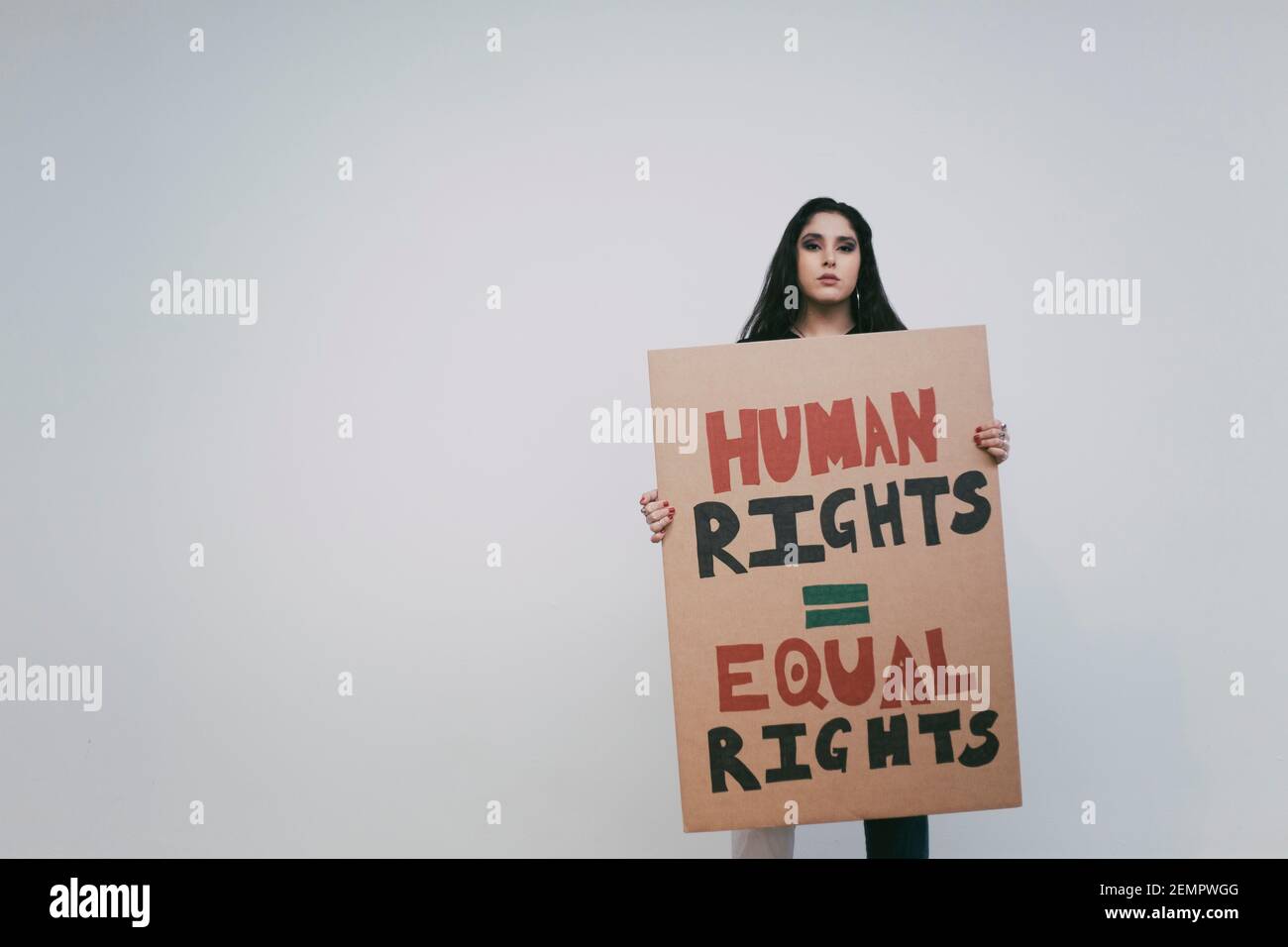 Attivista femminile con cartello per i diritti umani contro il muro bianco Foto Stock