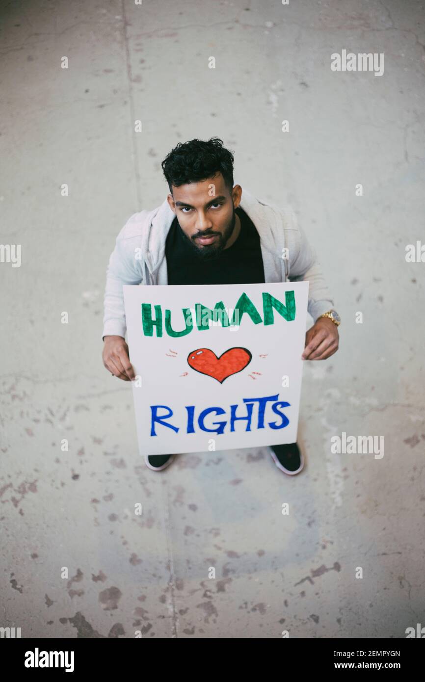 Ritratto ad alto angolo del protestore maschile che tiene un poster dei diritti umani Foto Stock
