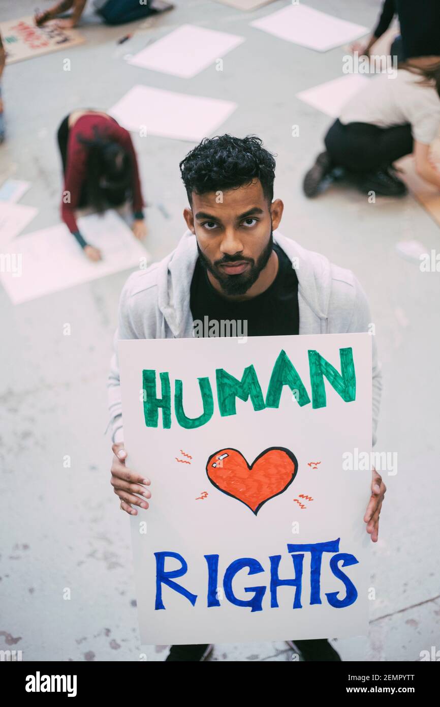 Attivista maschile che tiene un poster sui diritti umani durante le questioni sociali Foto Stock