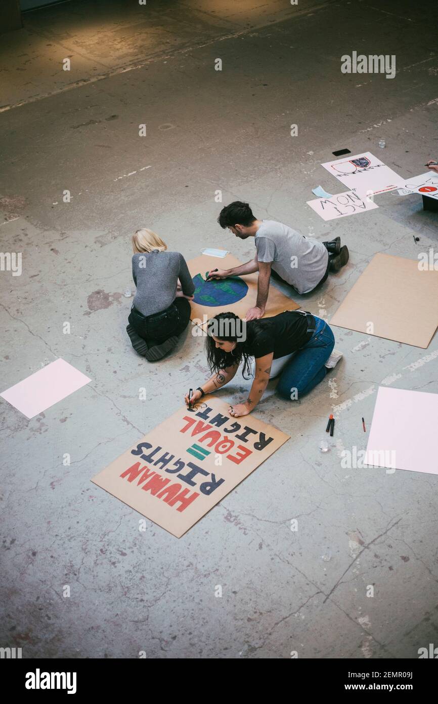 Vista ad alto angolo dei manifestanti maschili e femminili che fanno poster per pari diritti e questioni ambientali Foto Stock