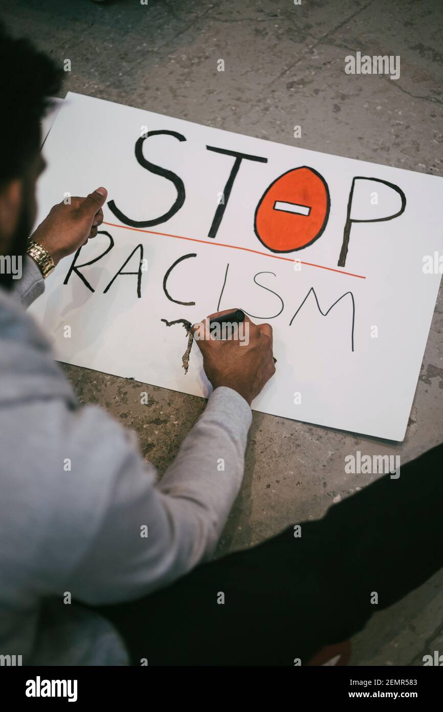 Vista ad alto angolo dell'uomo che fa un cartello di razzismo in edificio Foto Stock