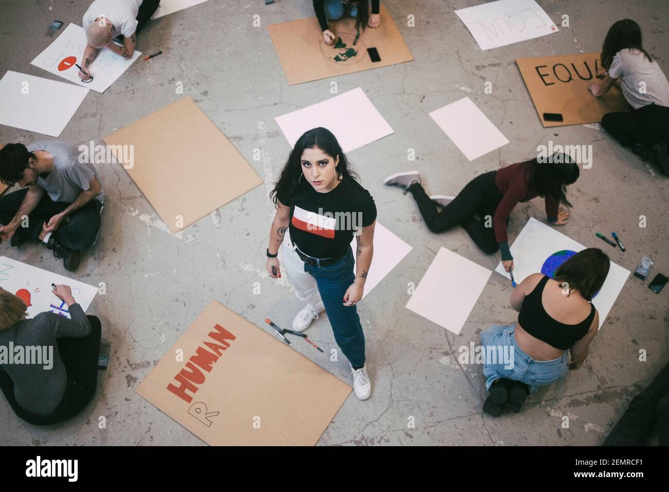 Ritratto ad alto angolo di donna in piedi mentre maschio e femmina attivista che prepara cartelli in costruzione Foto Stock