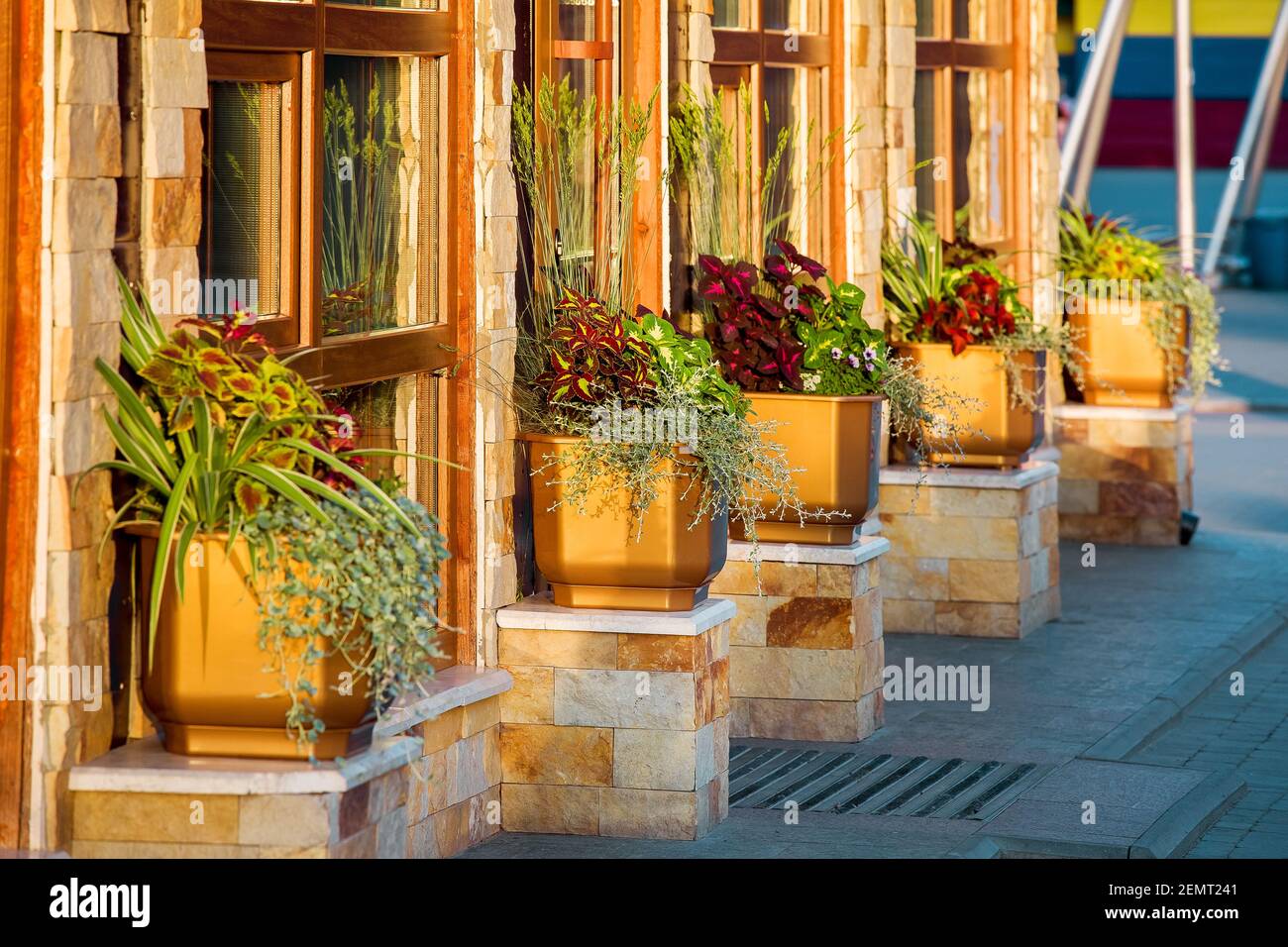 facciata di un edificio in piastrelle di pietra con finestre marroni e piantane  per vasi di fiori nella strada illuminata dalla luce del sole vista  laterale da vicino, nessuno Foto stock -