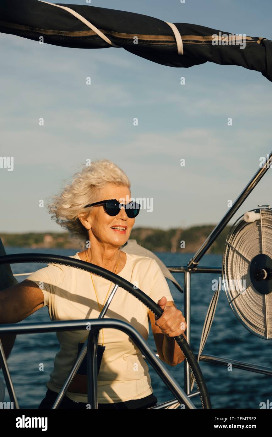 Donna anziana sorridente barca a vela in mare in giornata di sole Foto Stock
