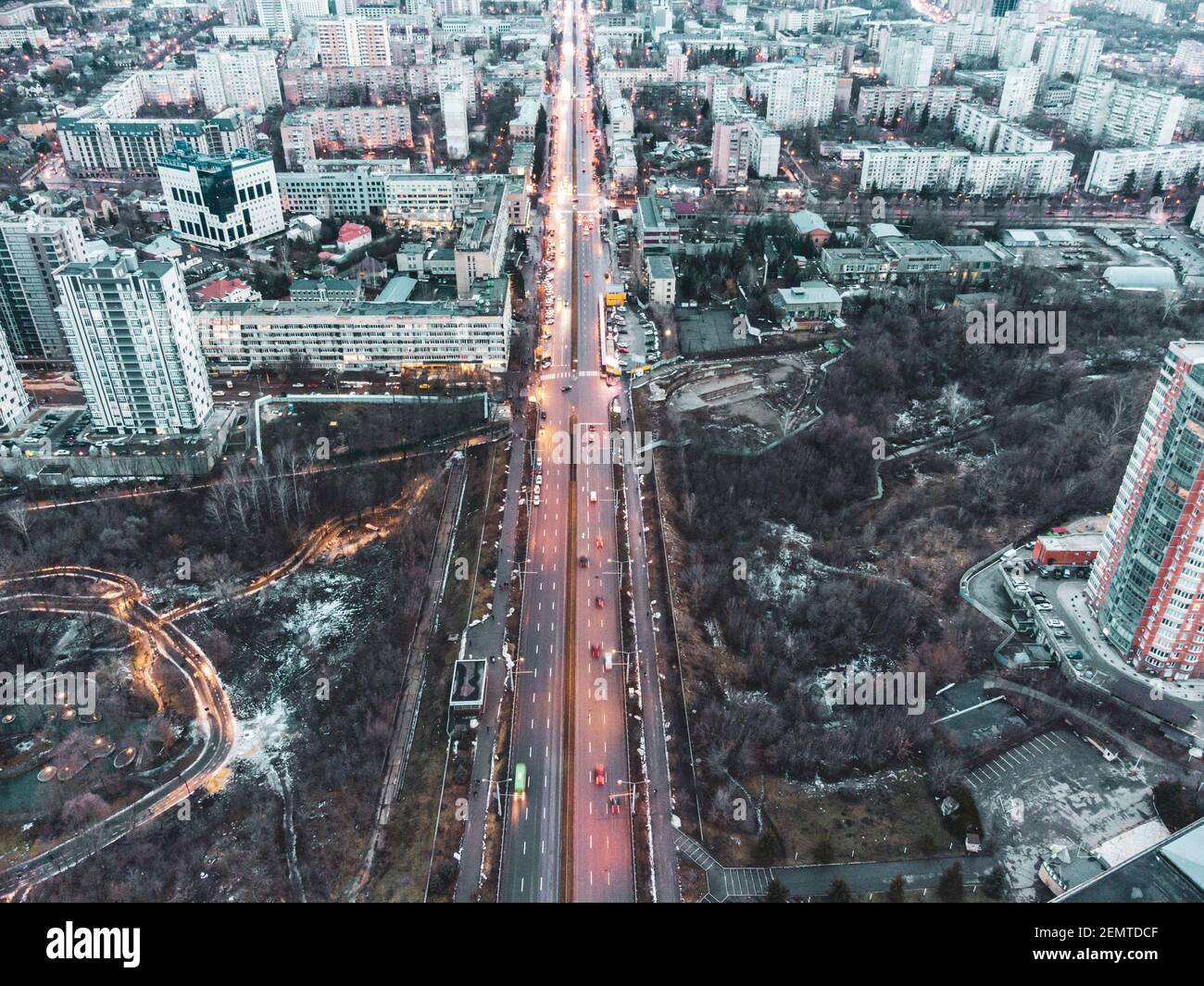 Vista aerea del centro di Kharkiv nauky ave. Giardino botanico Sarzhyn Yar e edifici moderni a più piani in serata. Città grigia d'inverno con strada rossa Foto Stock