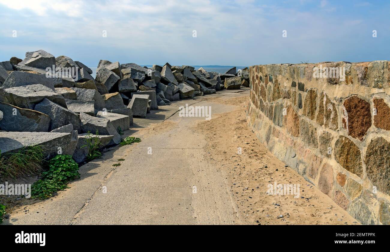 Via su una talpa tra blocchi di granito come wave breakers e un muro di pietra verticale al porto di Sassnitz, Germania Foto Stock