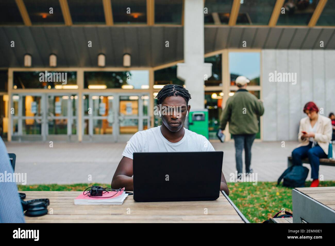 Giovane studente di sesso maschile che si concentra durante l'e-learning sul laptop in università Foto Stock