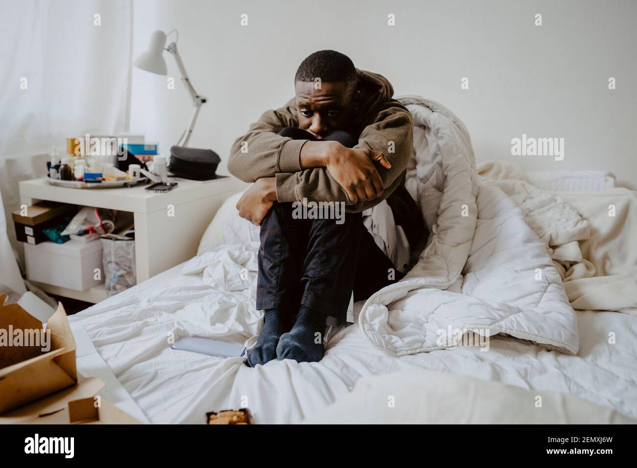 Uomo depresso seduto a letto a casa Foto Stock