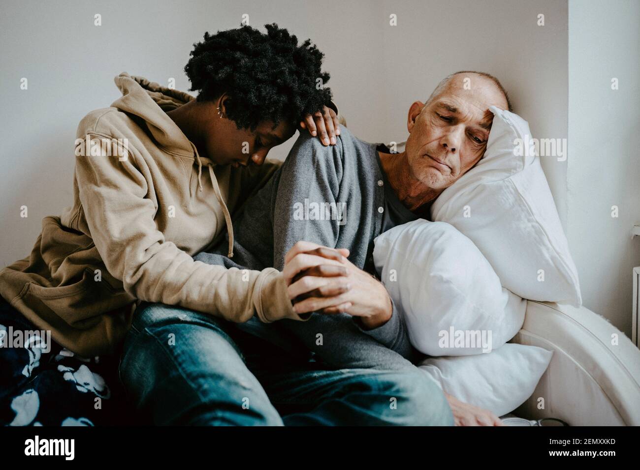 Padre e figlia depressi che tengono le mani a casa Foto Stock