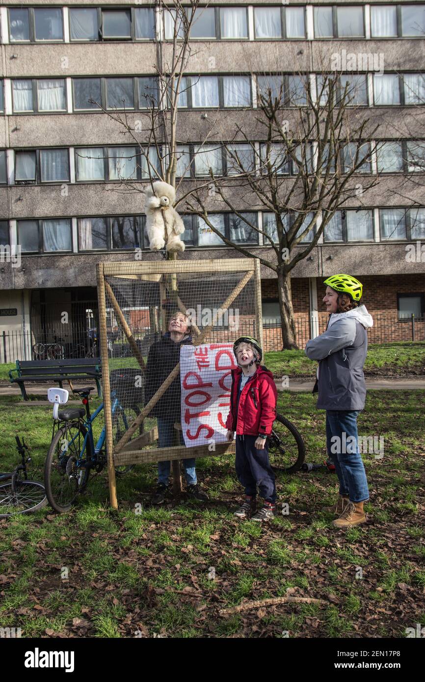 Londra, Regno Unito. 23 febbraio 2021. STOP THE CHOP dice un banner portato a Londra dagli York Gardens, Battersea, da un residente locale e dai suoi due figli. Vogliono mostrare sostegno ai tre attivisti che occupano un albero di pioppo nero di 100 anni per risparmiarlo dal abbattimento. L'albero era dovuto per abbattimento per fare il posto ad un nuovo cavo elettrico, parte del programma locale di rigenerazione dell'alloggiamento. Ma l'albero di pioppo, un albero di valore di alta amenità di categoria, può essere abbattuto soltanto se ci sono motivi costringenti tagliarlo giù. Molti bambini usano giocare nel parco sotto questo vecchio albero. Foto Stock