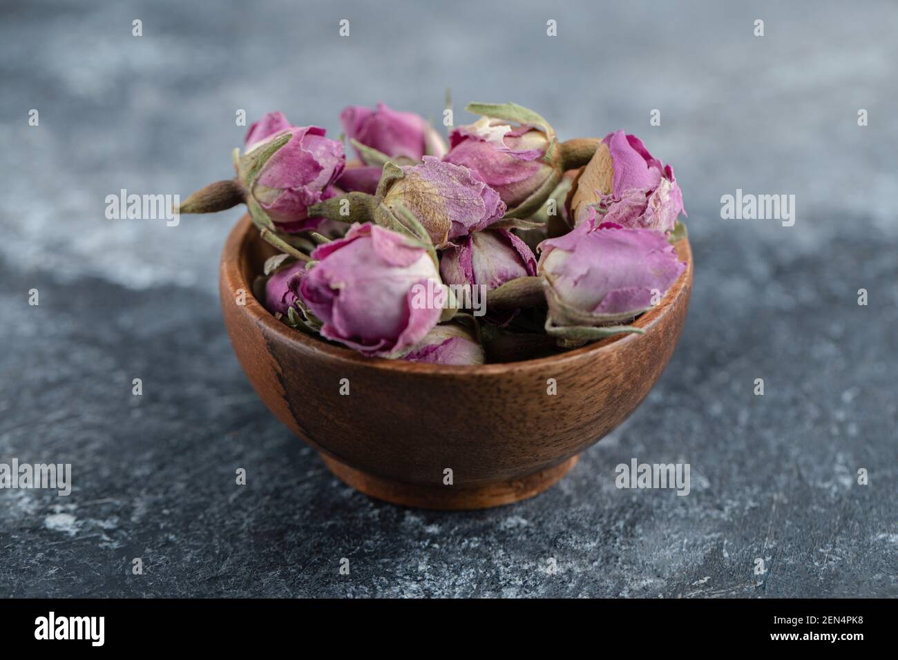 Piccole rose in erba in ciotola di legno Foto Stock