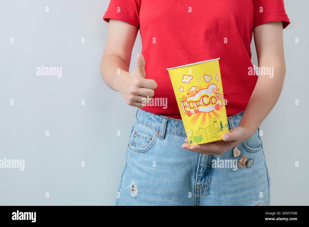 Ragazza giovane in camicia rossa che tiene un secchio di popcorn Foto Stock