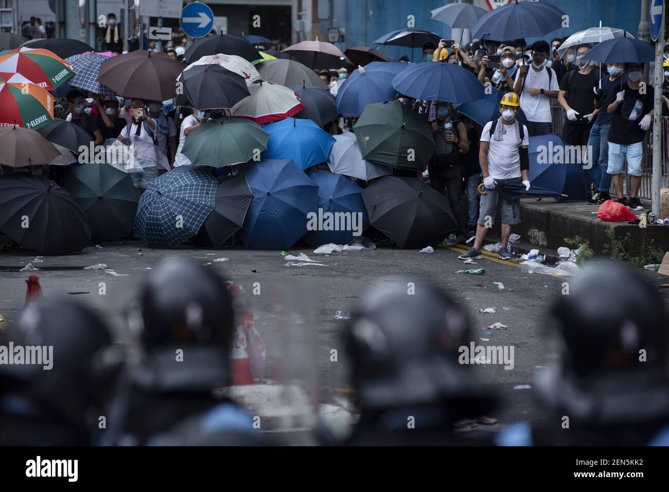 I manifestanti si prendono la copertura con ombrelli per un prossimo  attacco di gas lacrimogeni durante la dimostrazione. Migliaia di  manifestanti hanno occupato le strade vicino al complesso del Consiglio  legislativo di