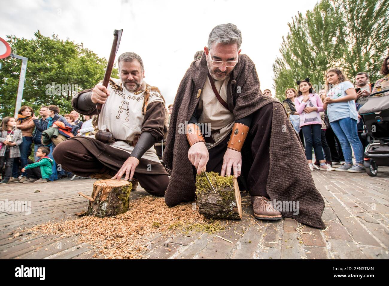 Due uomini vestiti come celtici che lavorano il legno con un'ascia e un  coltello nel festival Arde Lucus. Arde Lucus, celebrato in città dal 2001  alla fine di giugno, è un festival