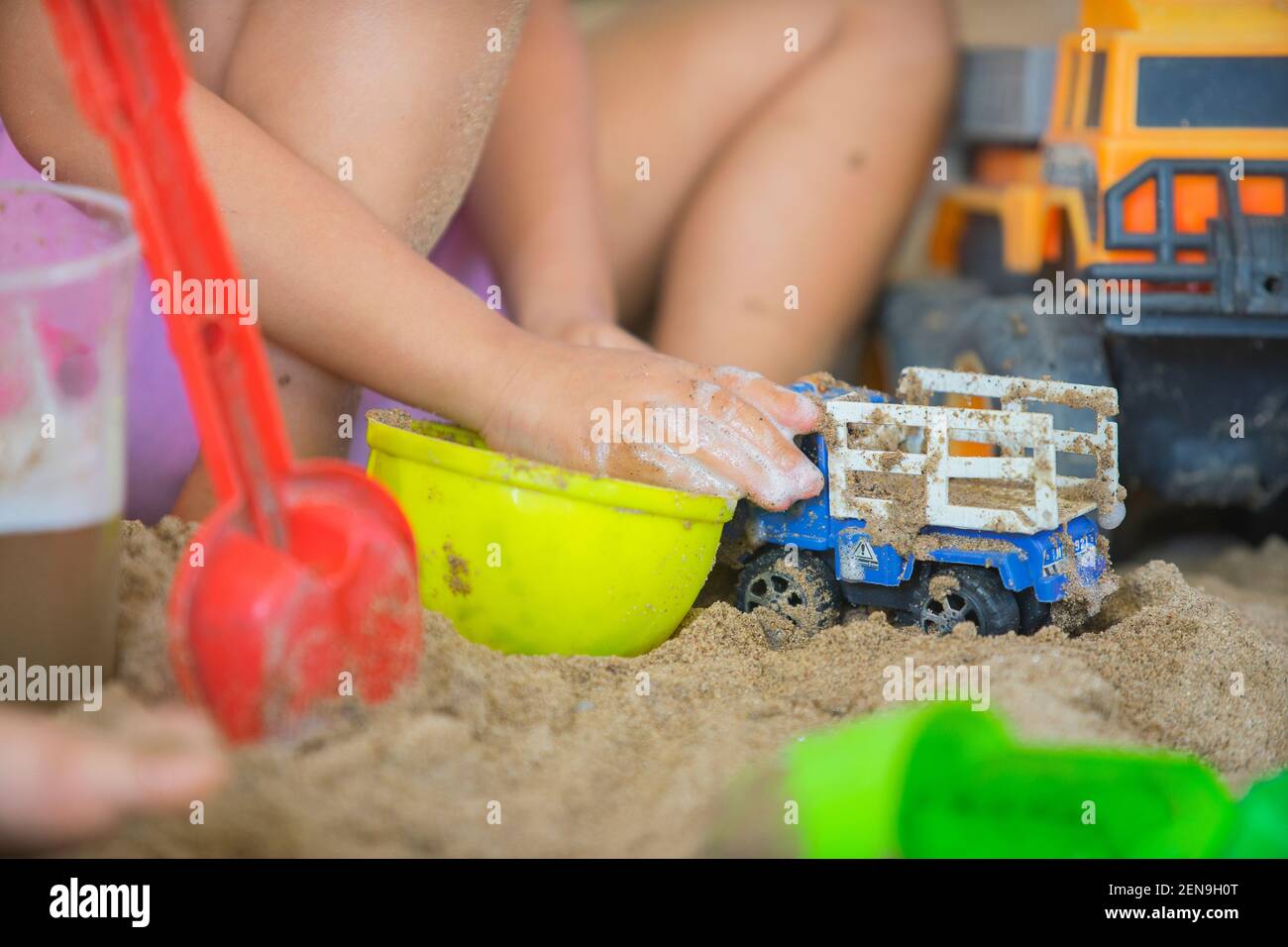 Piccolo ragazzo che gioca con i bambini camion nel sandpit. Foto Stock