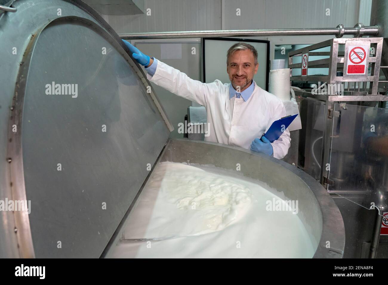 Ritratto di Food Engineer in Dairy Plant. Pastorizzazione del latte nell'impianto di lavorazione dei latticini. Latte all'interno del serbatoio di pastorizzazione. Caseificio sicurezza alimentare. Foto Stock