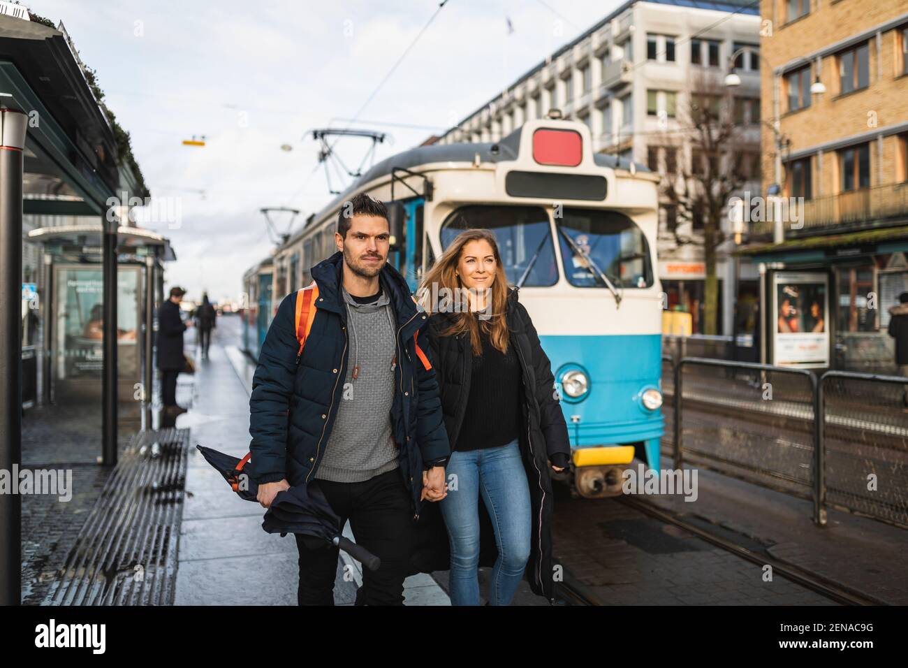 Coppia che tiene le mani mentre si cammina alla stazione del tram Foto Stock