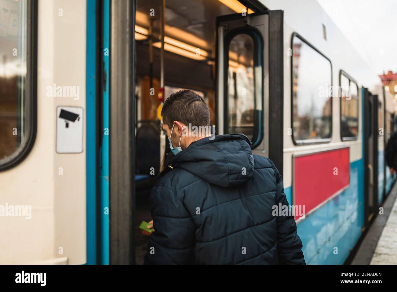Uomo di mezza età che salpano sul tram durante la pandemia Foto Stock