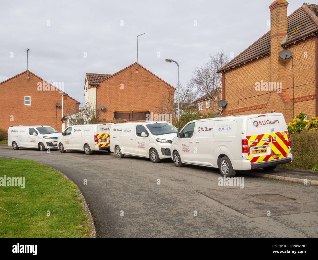 Quattro furgoni bianchi della ditta appaltatrice Openreach hanno parcheggiato il naso alla coda in una strada suburbana, Northampton, Regno Unito; adattando la banda larga in fibra ad una casa. Foto Stock