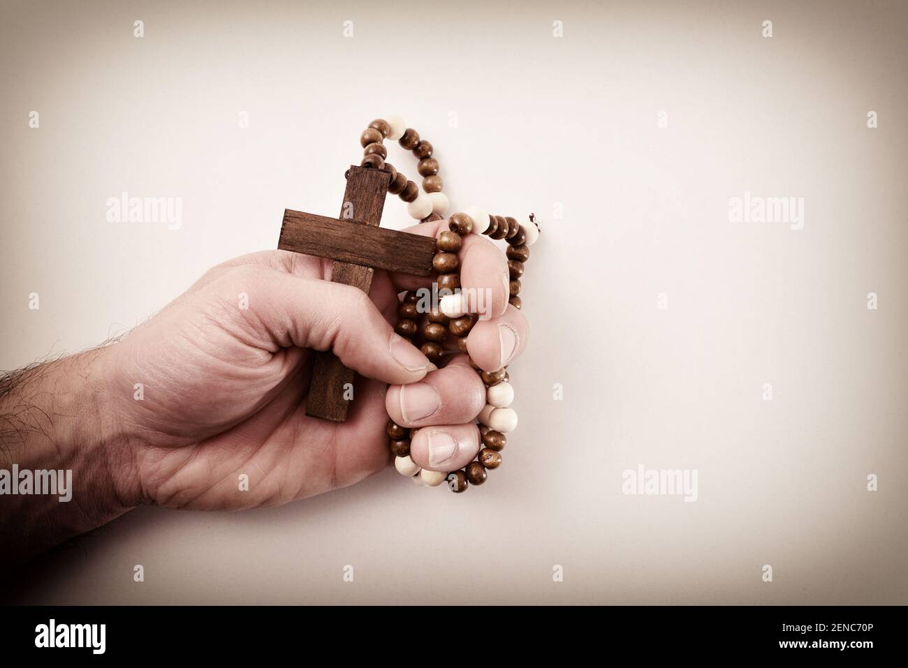 Mano di un religioso caucasico che stringe con colpa pentimento una croce marrone scuro con collana rotonda in perle di legno pregare con bac isolato Foto Stock