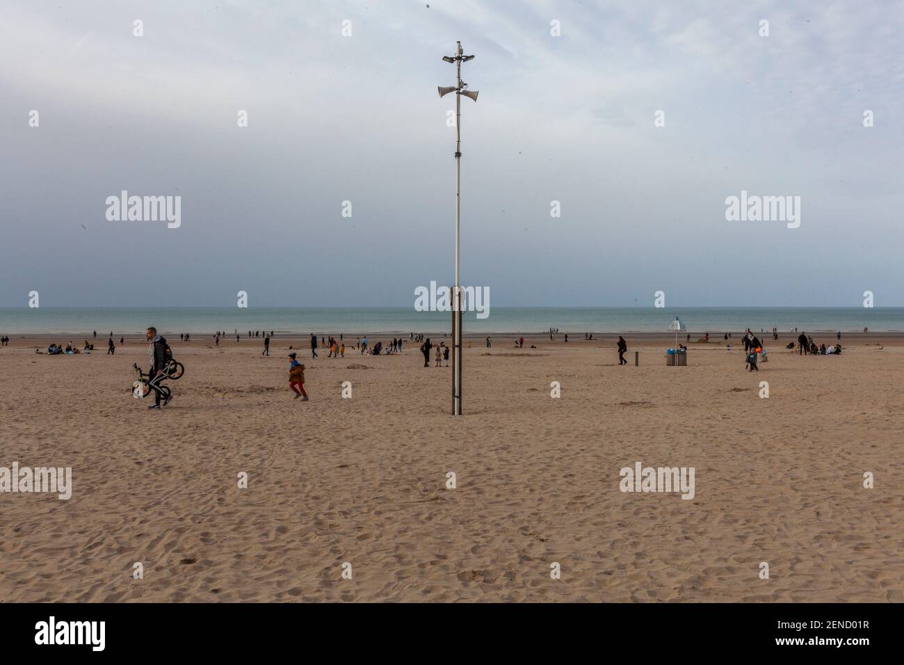 Mentre il primo fine settimana di sole e buon tempo si stabilizza dopo diversi giorni di temperature negative nel paese, e le misure di contenimento e la lotta contro il covid sono ancora efficaci, i turisti si affollano nella piccola città di mare al confine con la Francia. I turisti vanno in spiaggia e passano davanti a un caffè vuoto che è chiuso a causa del COVID. Foto Stock