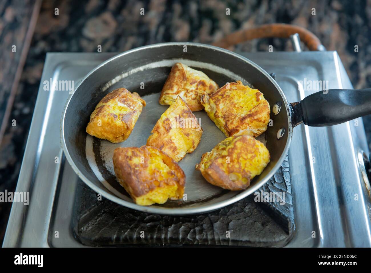 Pane Burger tagliato a pezzi e immergere in tuorlo d'uovo mescolato con sale e fritto con ghee su una padella. Pane fritto Burger, spuntini per la colazione Foto Stock