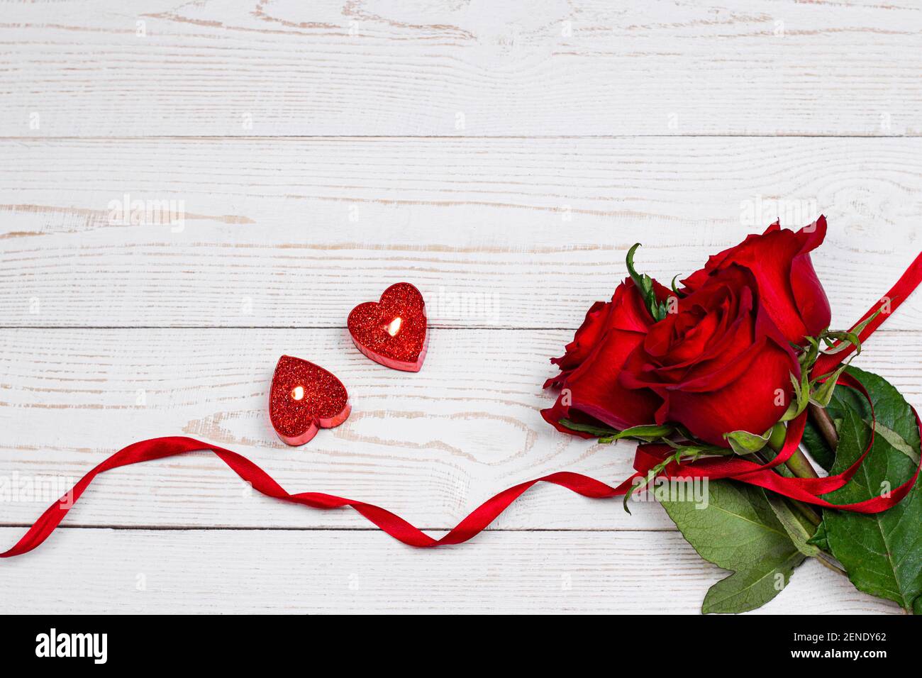 Romantico Sfondo San Valentino. Candele accese e cuori rossi decorati con  fiori bianchi Foto stock - Alamy