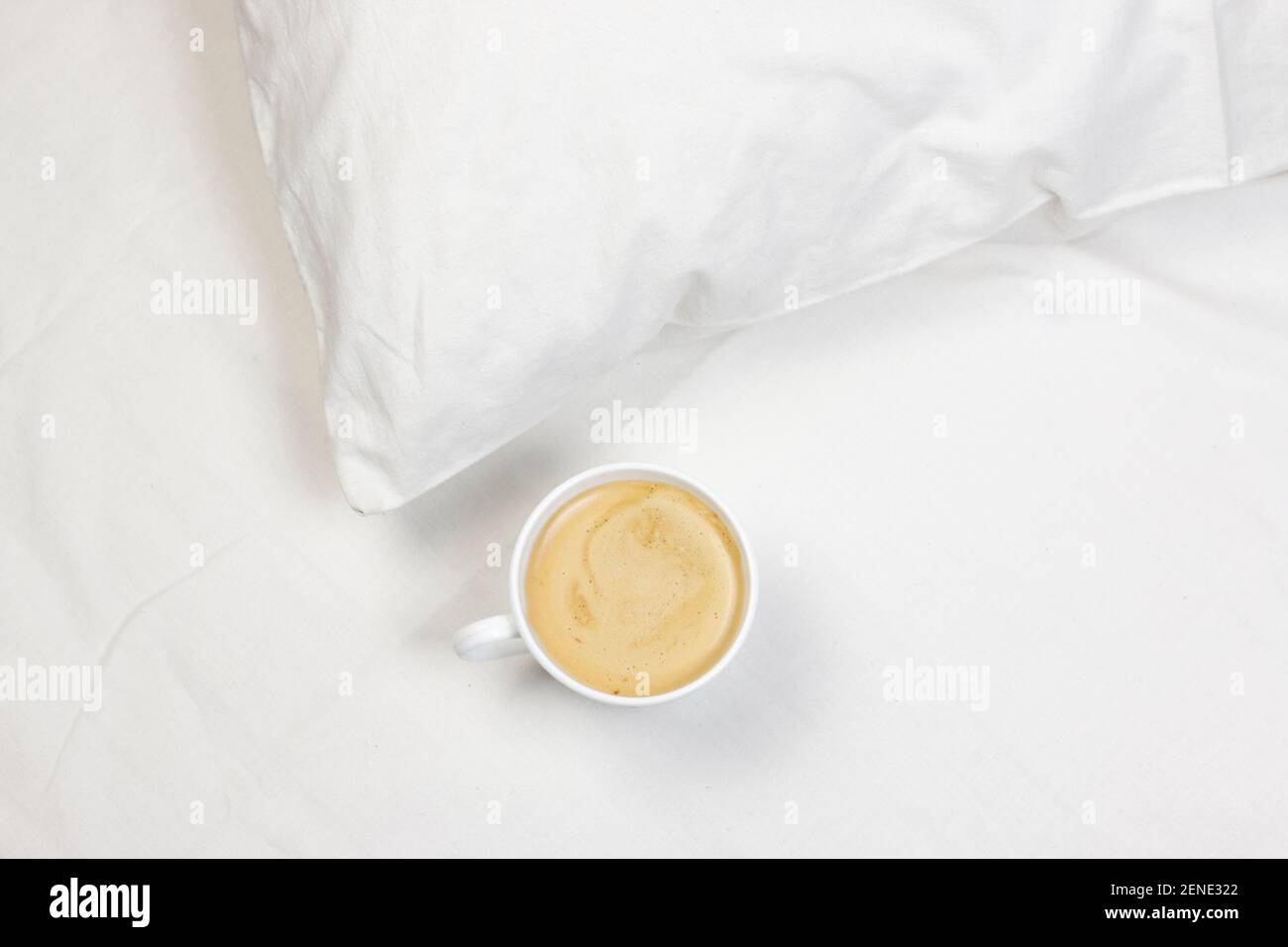 Tazza di caffè sul letto bianco. Mattina, romantico rilassa lo sfondo piatto. Foto Stock