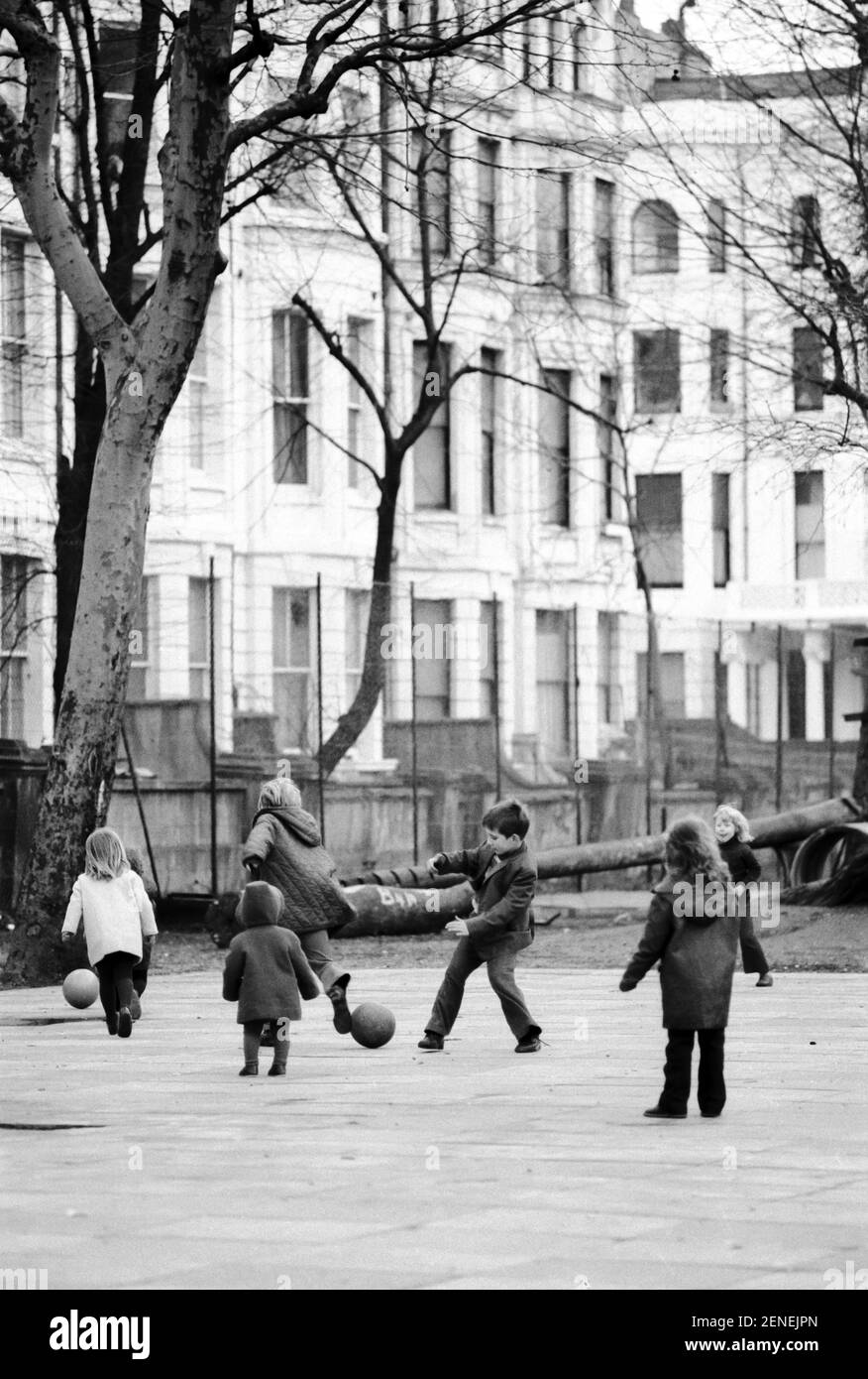 UK, West London, Notting Hill, 1973. Rundown e faticosamente grandi case a quattro piani stanno iniziando ad essere restaurate e ridecorate. I bambini giocano intorno alla zona di Powis Square. Foto Stock
