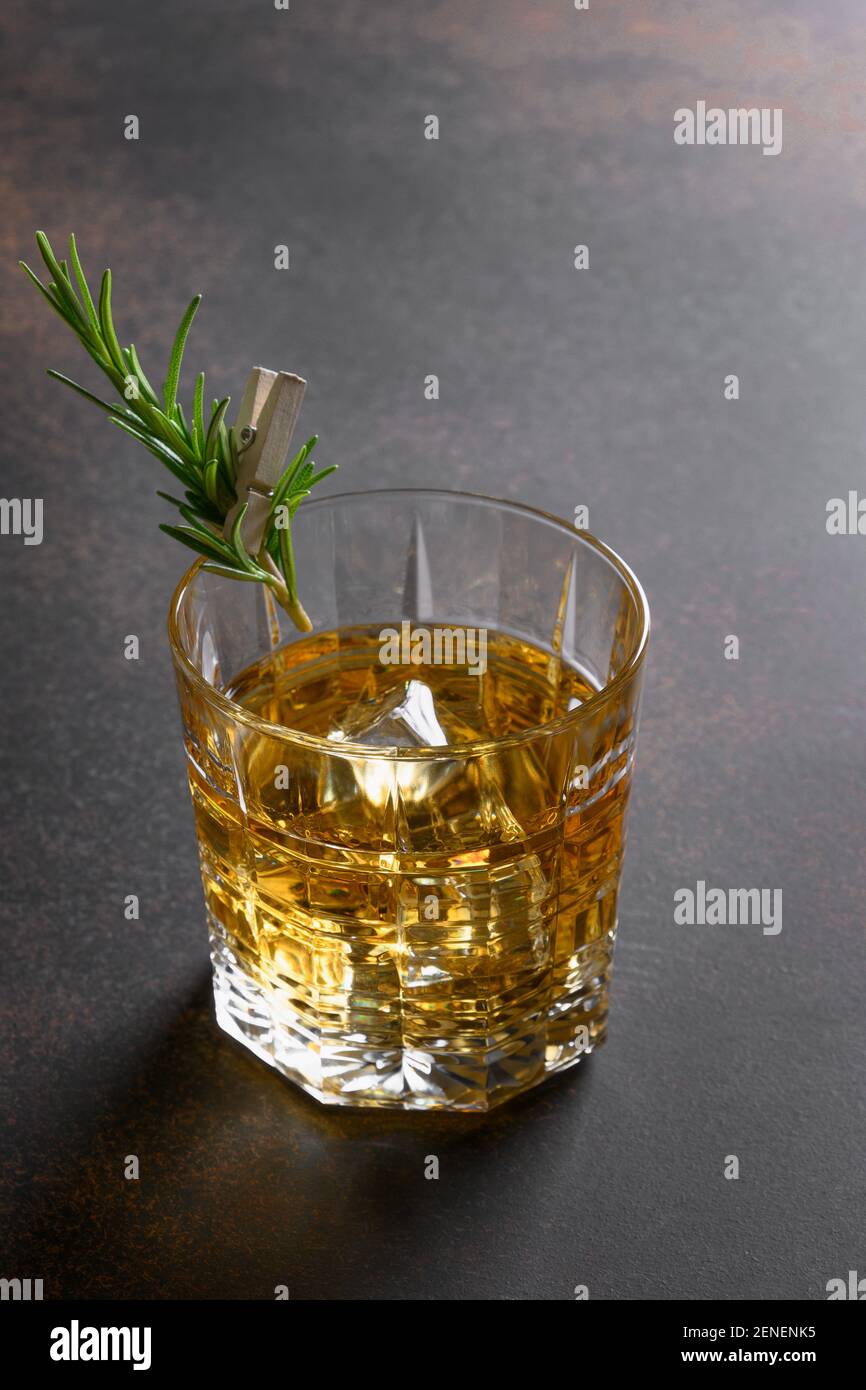 Un colpo di whisky con cubetto di ghiaccio su sfondo marrone scuro. Foto Stock
