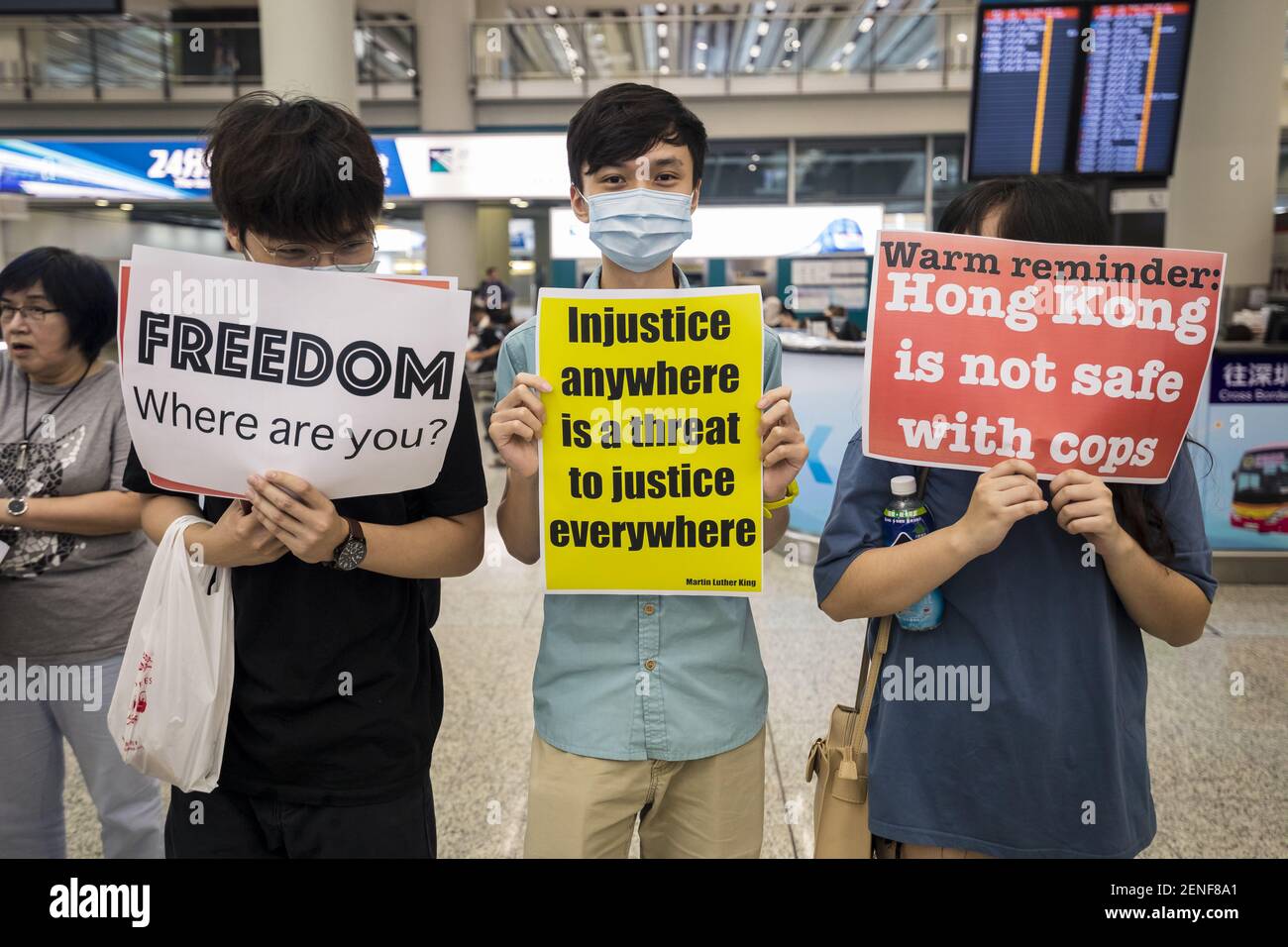 Manifestanti esibendo cartelli in inglese durante la protesta in aeroporto.  Migliaia di manifestanti si sono dati nella sala degli arrivi dell'aeroporto  internazionale di Hong Kong con il nome di "saluti dall'Assemblea HKers"