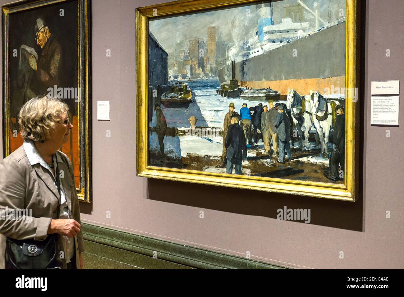 Una donna guarda il 'Men of the dock' di George Bellows. Brooklyn dock scena New York..Vintage dipinti marini alla National Gallery London Inghilterra Foto Stock