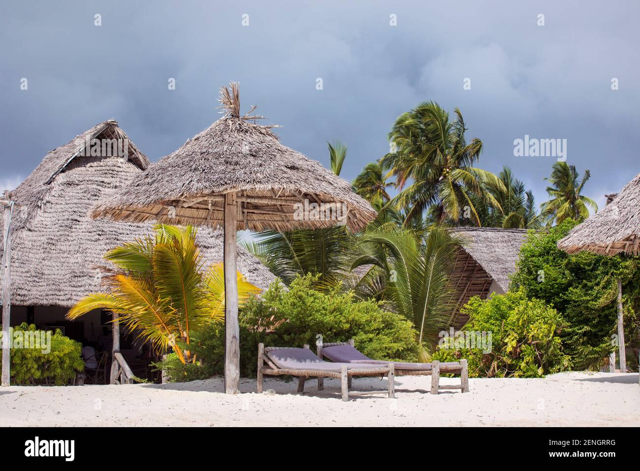 Resort turistico su una spiaggia tropicale con sabbia bianca sotto palme. Lettini e ombrellone. Vacanze da sogno per il clima tropicale. Foto Stock