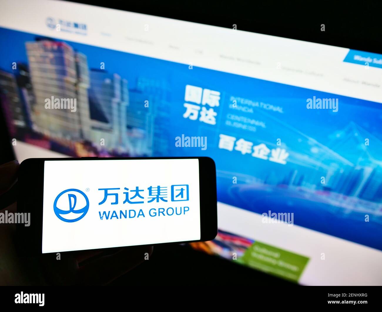 Persona che tiene uno smartphone con il logo del conglomerato cinese Wanda Group sullo schermo davanti al sito web. Mettere a fuoco il display del telefono. Foto non modificata. Foto Stock