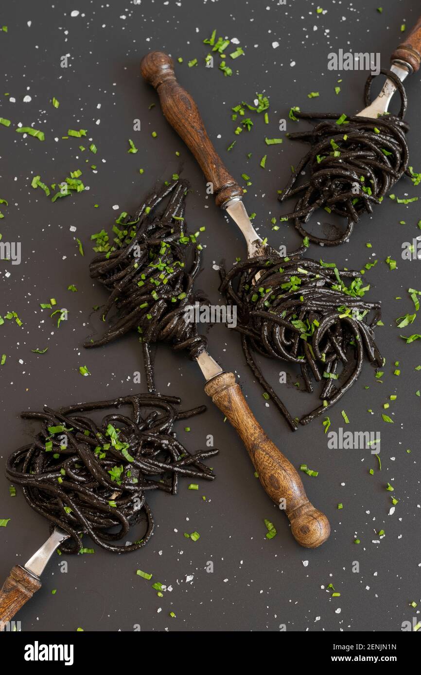 Spaghetti neri con inchiostro di seppie. Pasta di pesce nera su sfondo scuro. Gastronomia mediterranea. Foto Stock