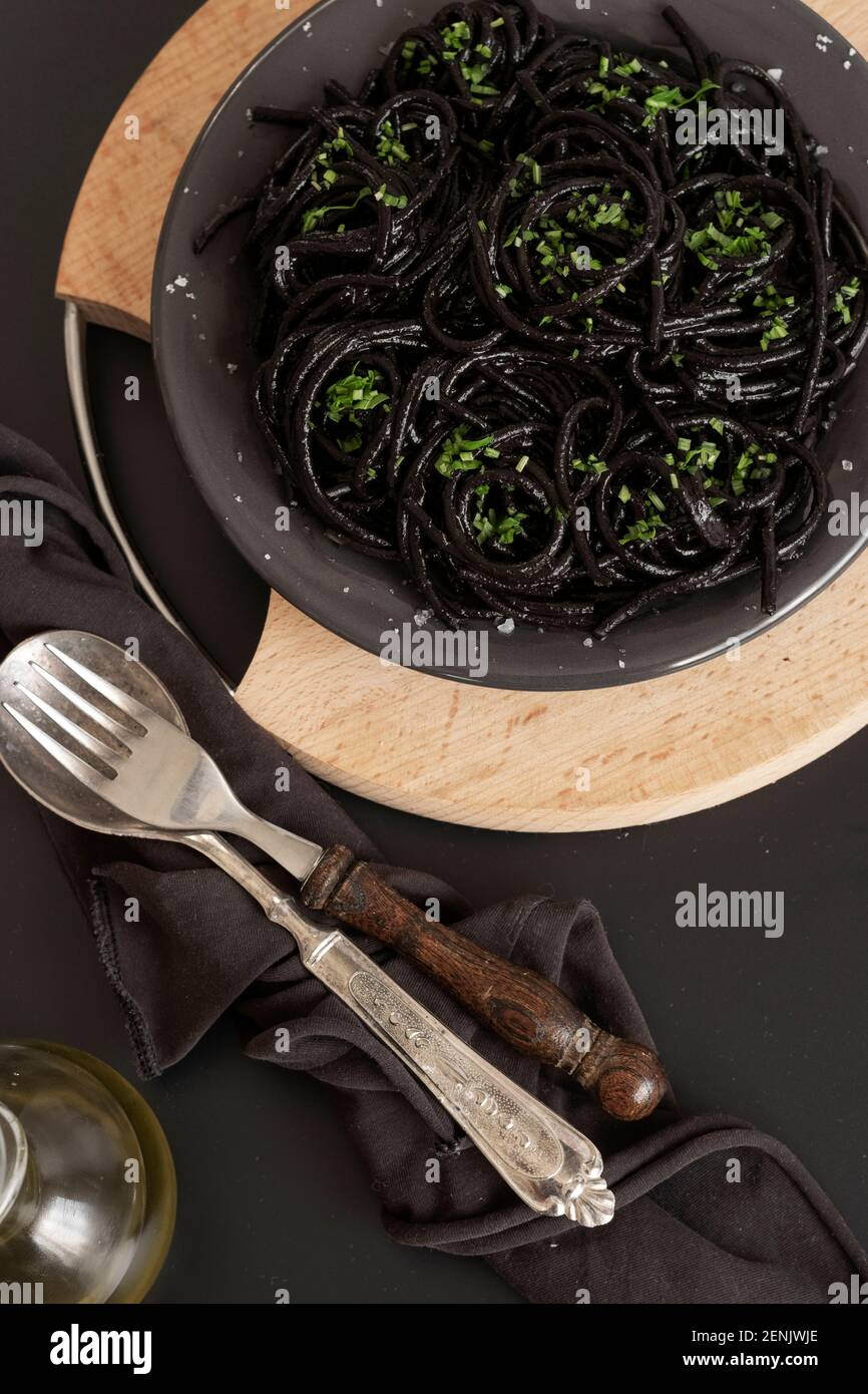 Spaghetti neri con inchiostro di seppie. Pasta di pesce nera su sfondo scuro. Gastronomia mediterranea. Foto Stock