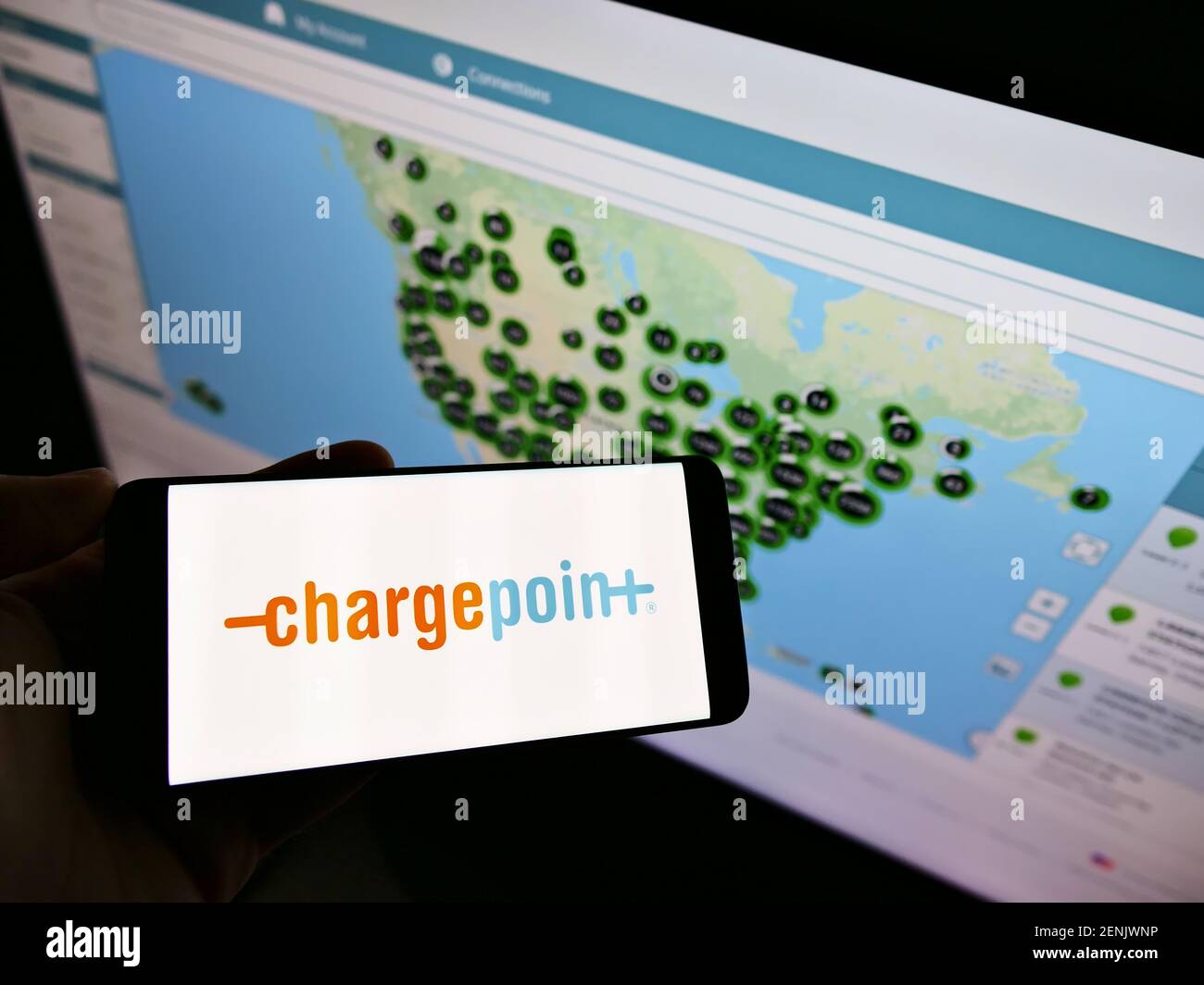 Persona che tiene il telefono cellulare con il logo aziendale della società americana ChargePoint Holdings Inc sullo schermo di fronte alla pagina web con la mappa. Mettere a fuoco il display del telefono. Foto Stock