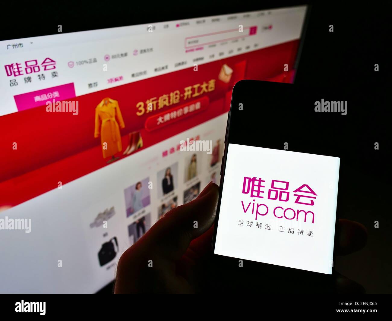 Persona titolare cellulare con logo della società cinese di e-commerce Vipshop Holdings (VIP.com) sullo schermo davanti alla pagina web. Mettere a fuoco il display del telefono. Foto Stock