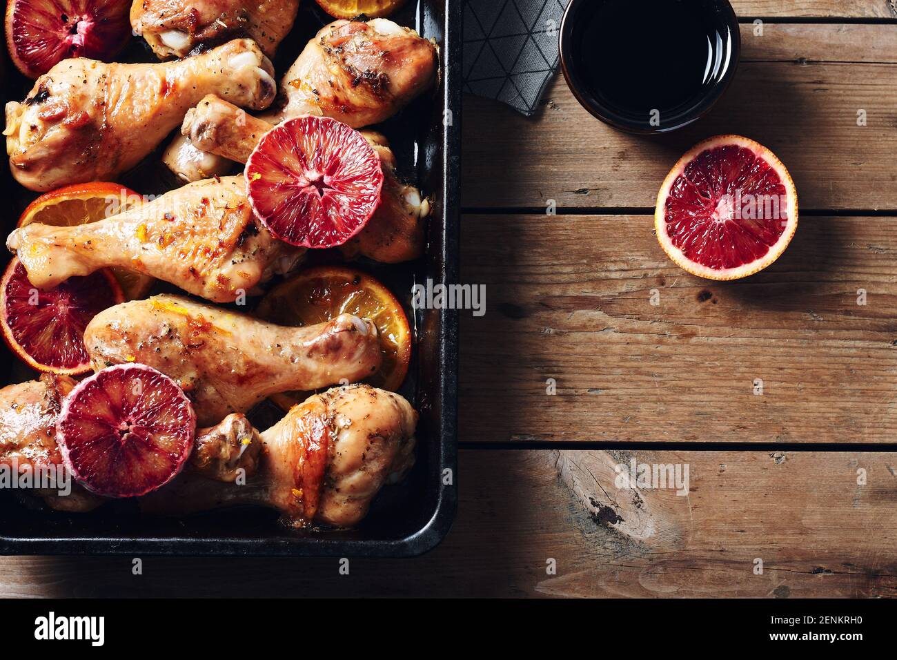 Bastone di pollo arrosto con spezie in padella. Cosce di pollo al forno con arance. Foto Stock