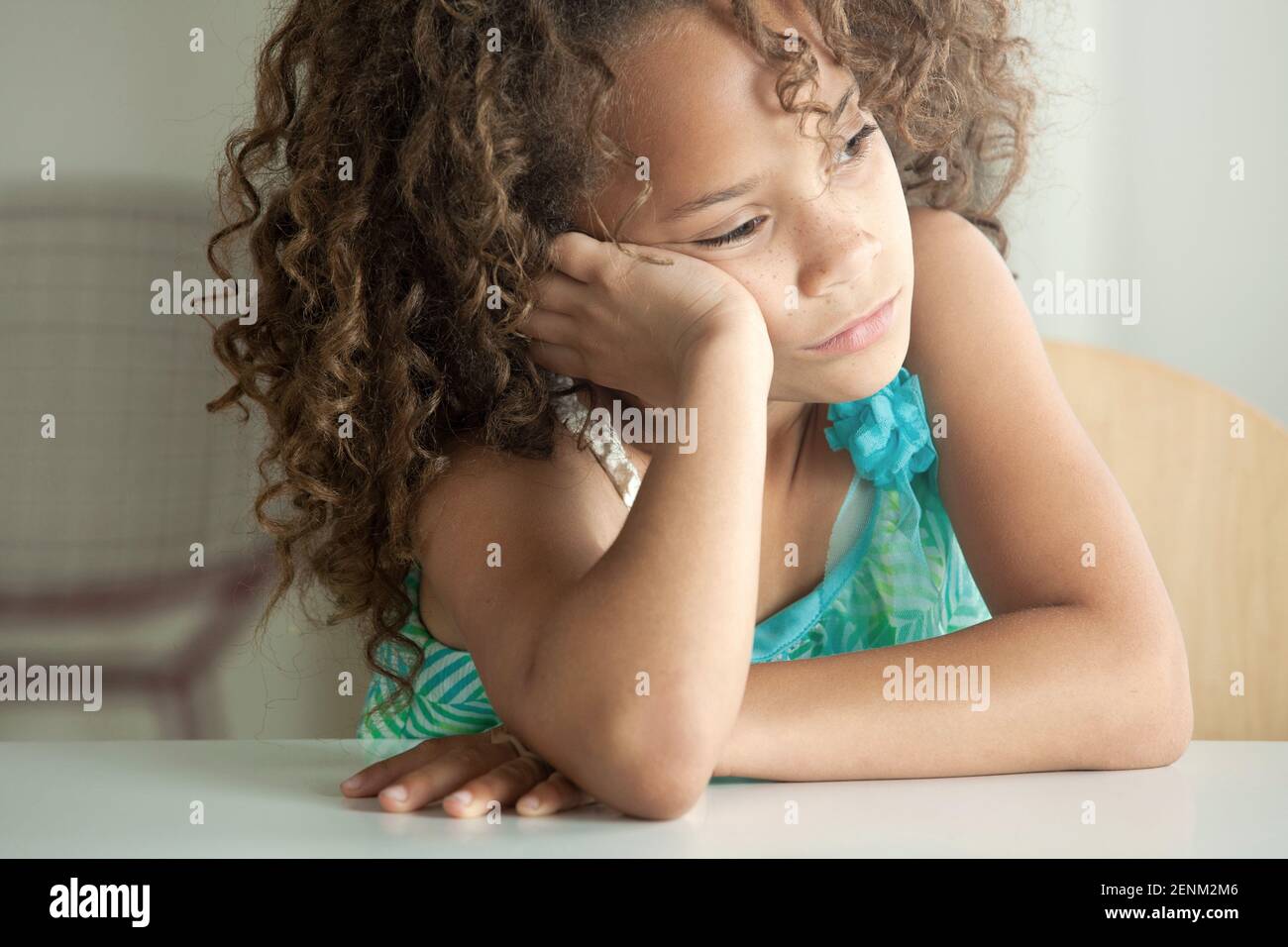 Ragazza appoggiata sul gomito guardando lontano Foto Stock