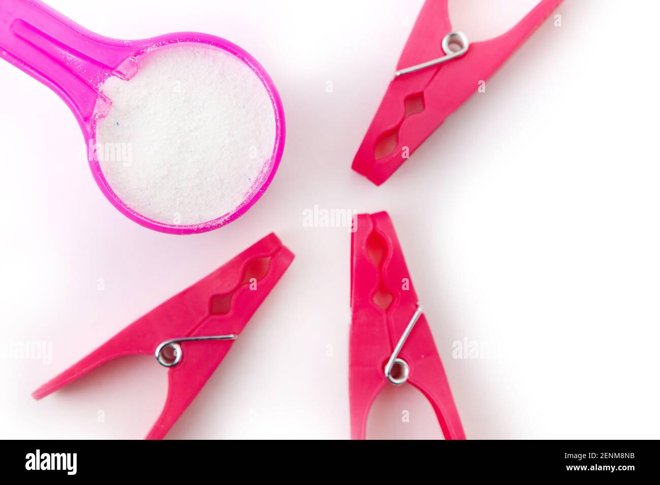 polvere di lavaggio in misurino rosa e stopine rosa su sfondo bianco Foto Stock