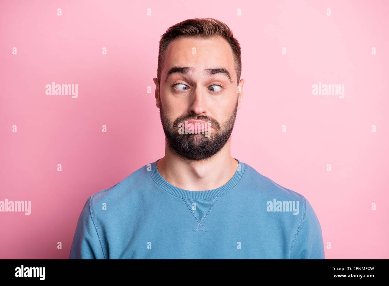 Foto di divertente giovane uomo freddo vestito pullover blu fooling naso che guarda isolato sfondo di colore rosa Foto Stock