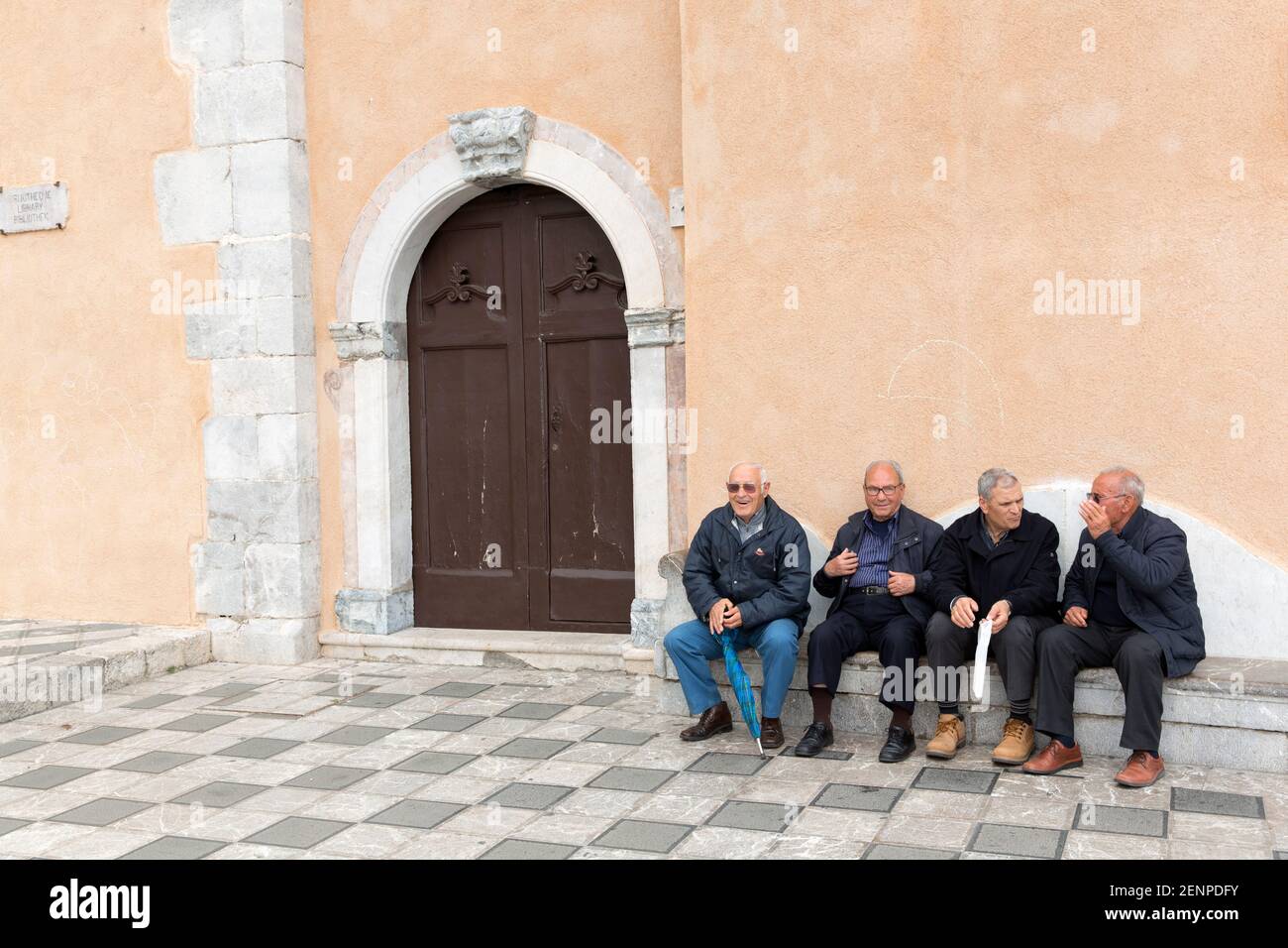 quattro signori anziani impegnati in una conversazione all'esterno in una piazza Foto Stock