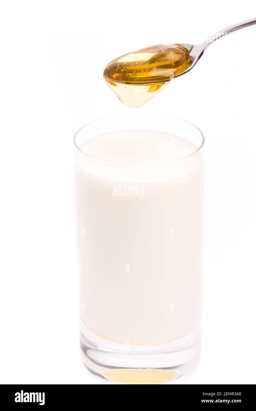 Bicchiere di latte al miele, latte, cucchiaio e miele su sfondo bianco Foto Stock