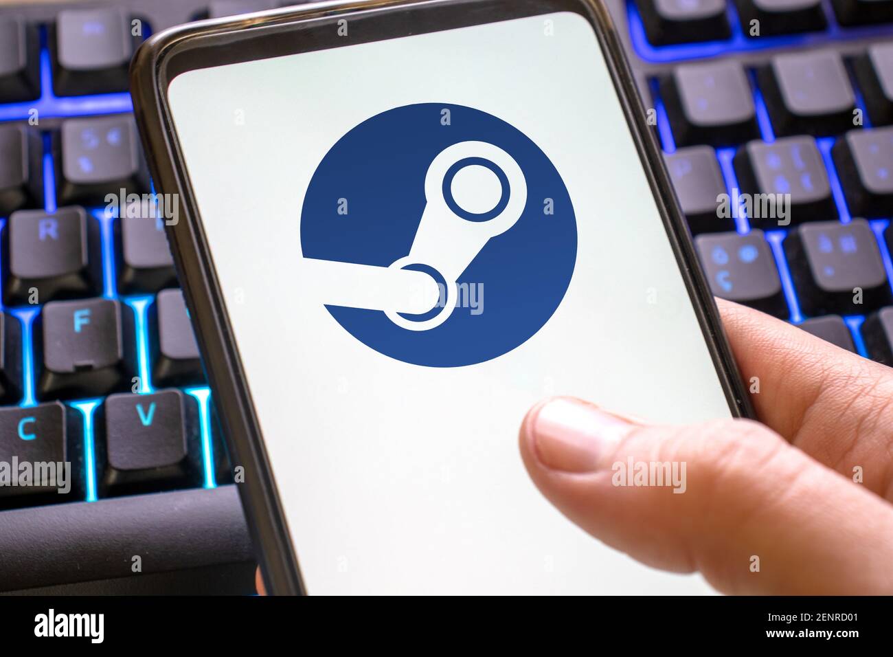 logo steam sullo schermo del telefono con sfondo blu della tastiera di gioco. icona della piattaforma di gioco per pc sul display dello smartphone. Italia, Milano, 26-02-21 Foto Stock