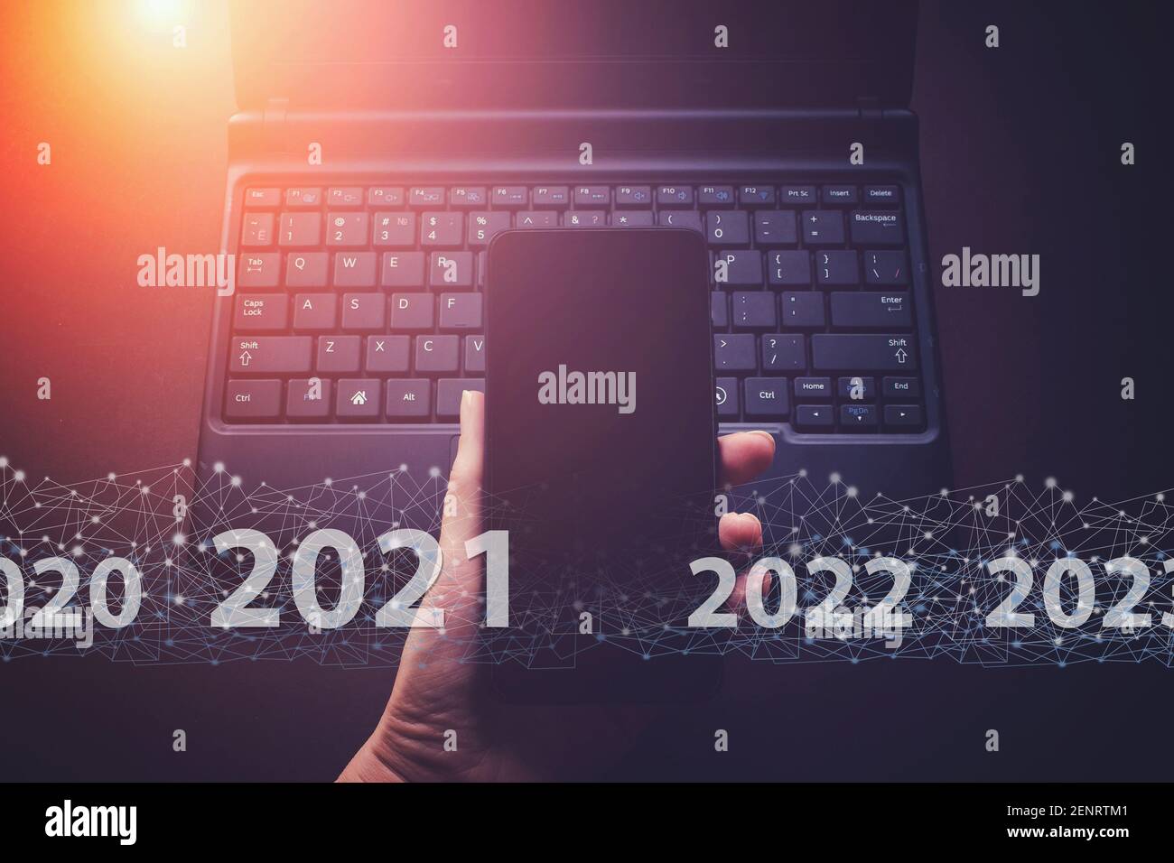 Tenere il telefono con la mano sullo sfondo della tastiera del notebook con il testo 2021. Creative Connection background, una rete di nuova generazione ha una velocità wireless l Foto Stock